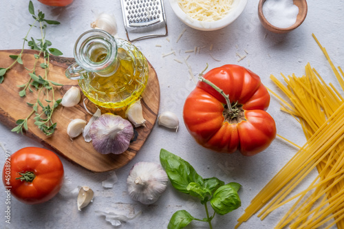Preparing an Italian meal with a chopping board, tomatoes, garlic, oil, basil, cheese and salt
