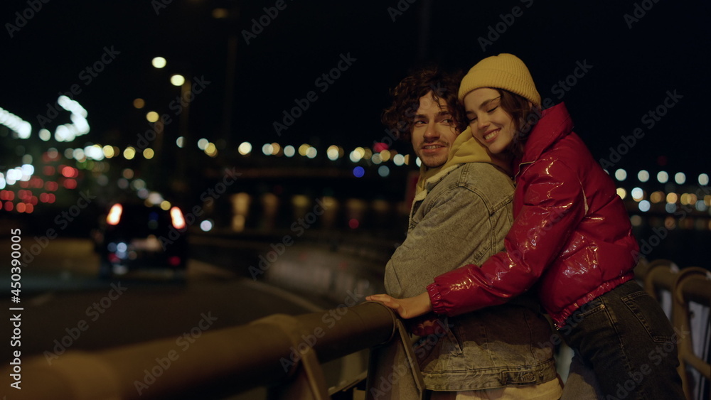 Happy couple spending date outdoor. Woman hugging man from back on city street.