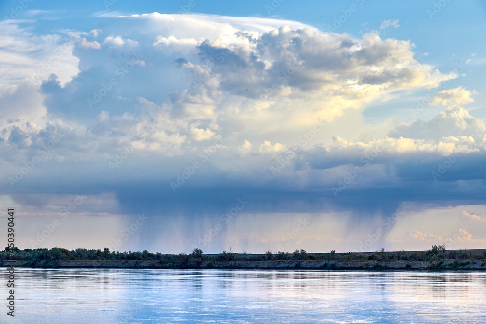 panoramic view of raining clouds over wide steppe river with a calm current panoramic view of raining clouds over wide steppe river with a calm current