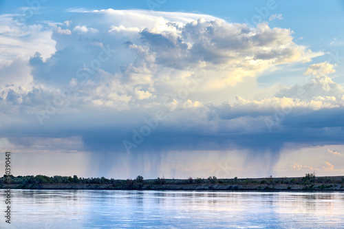 panoramic view of raining clouds over wide steppe river with a calm current