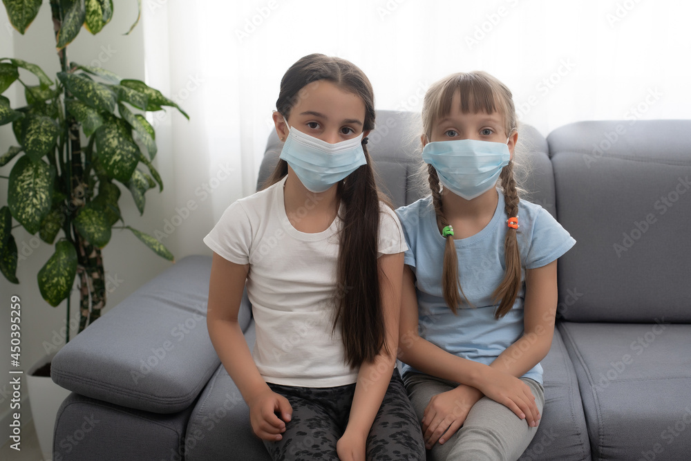 Indoor shot of little girls with wide opened eyes, wearing protective mask, Protection against coronavirus, covid 19 concept