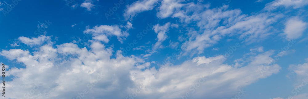 White clouds of different shapes on a blue sky, panorama