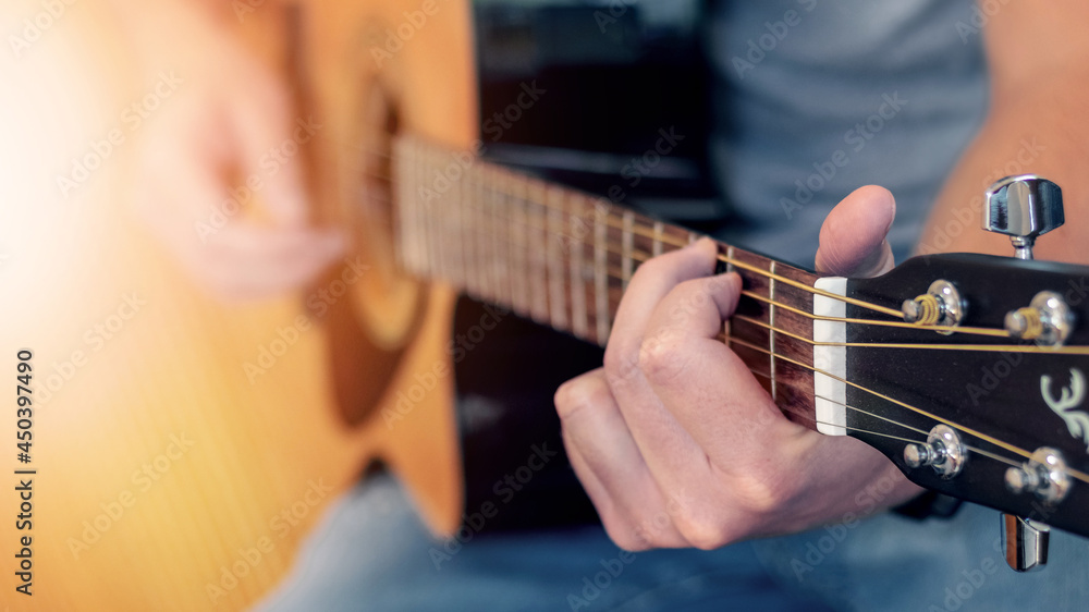 Man playing acoustic guitar, guitar close up at shallow depth of field