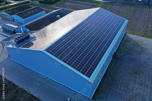 Solar panels on a roof of a company colored blue by sunlight. Solar panels are a cheap and sustainable way to get energy from sunlight. Photo taken with a flying drone
