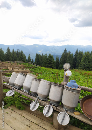 Cheese dairy at the top of the mountain. Milk cans dry on a wooden bench against the backdrop of the Carpathian mountains. photo