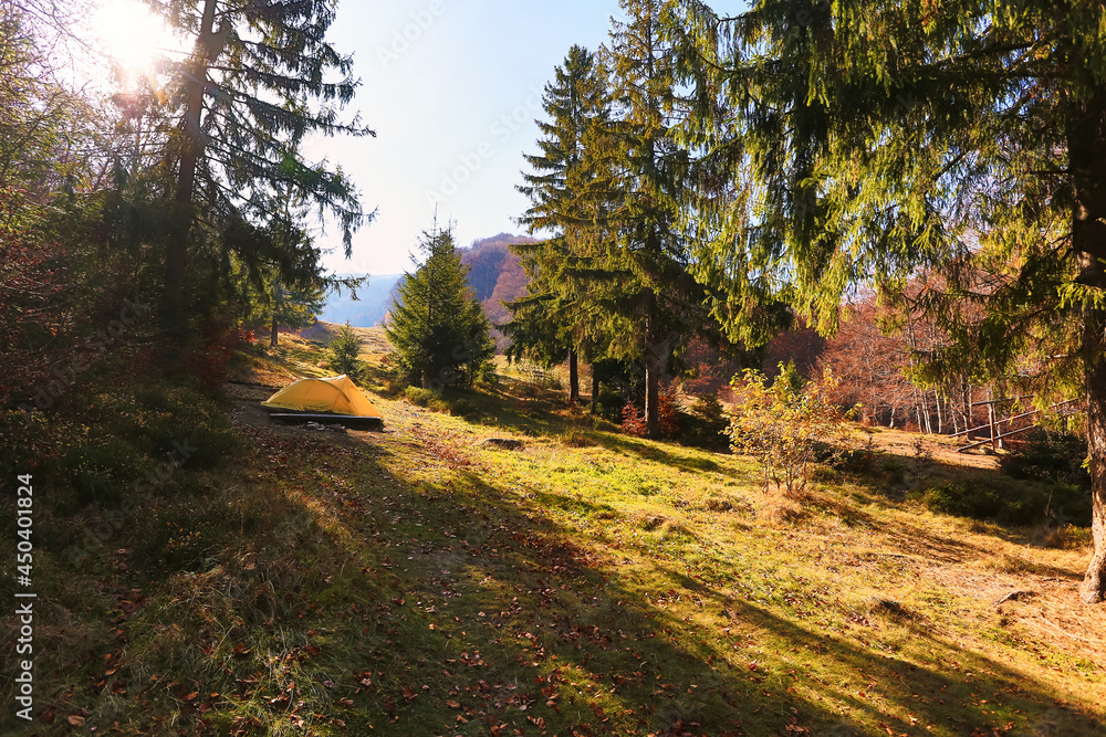 Beautiful autumn landscape with a tent in the forest. Fabulous autumn view of the mountain valley. Tourism concept. Dawn in a forest with a lonely tent Beautiful autumn landscape with a tent in the forest. Fabulous autumn view of the mountain valley. Tourism concept. Dawn in a forest with a lonely tent