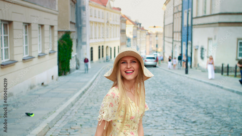 Cheerful pretty woman in white hat looking back at camera while walking in town. Cheerful pretty woman in white hat looking back at camera while walking in town.