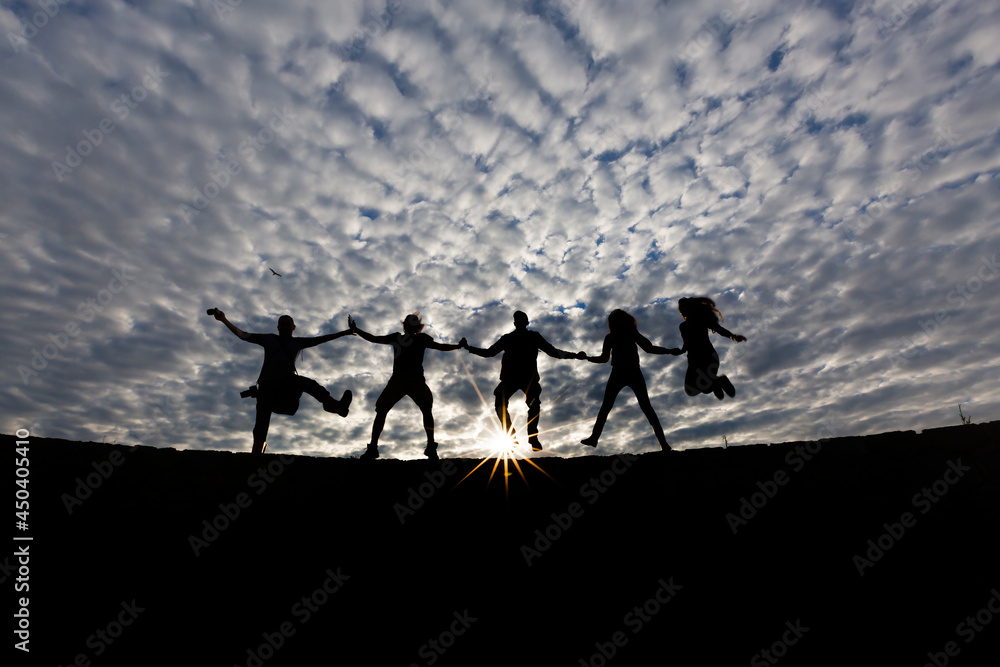 a gorgeous cloud in the back and silhouette models jumping hand in hand a gorgeous cloud in the back and silhouette models jumping hand in hand