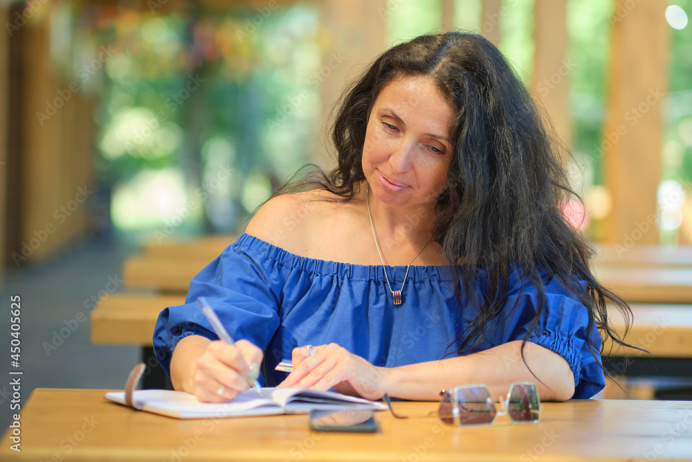 beautiful confident woman in a blue dress writes down her thoughts in a diary beautiful confident woman in a blue dress writes down her thoughts in a diary
