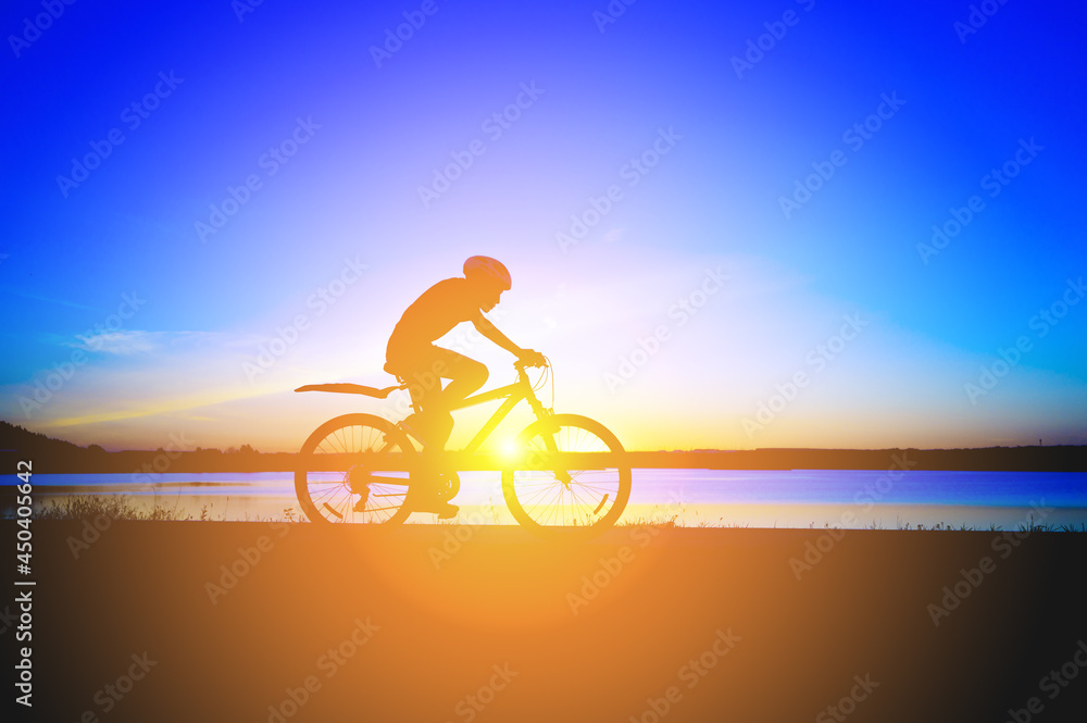 Fototapeta premium Unrecognizable silhouette man riding bicycle against sunset sky. Road biking cyclist workout, riding racing bicycle on open road. Workout for triathlon. Dramatic sunset background. side view