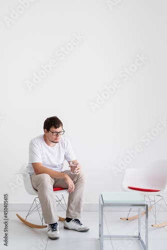 portrait of a tired man, stressed and with headache, holding glass of water