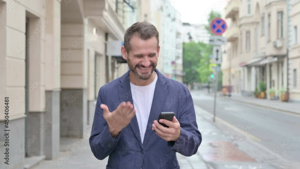 Man Celebrating Success on Phone while Walking Down the Street Man Celebrating Success on Phone while Walking Down the Street