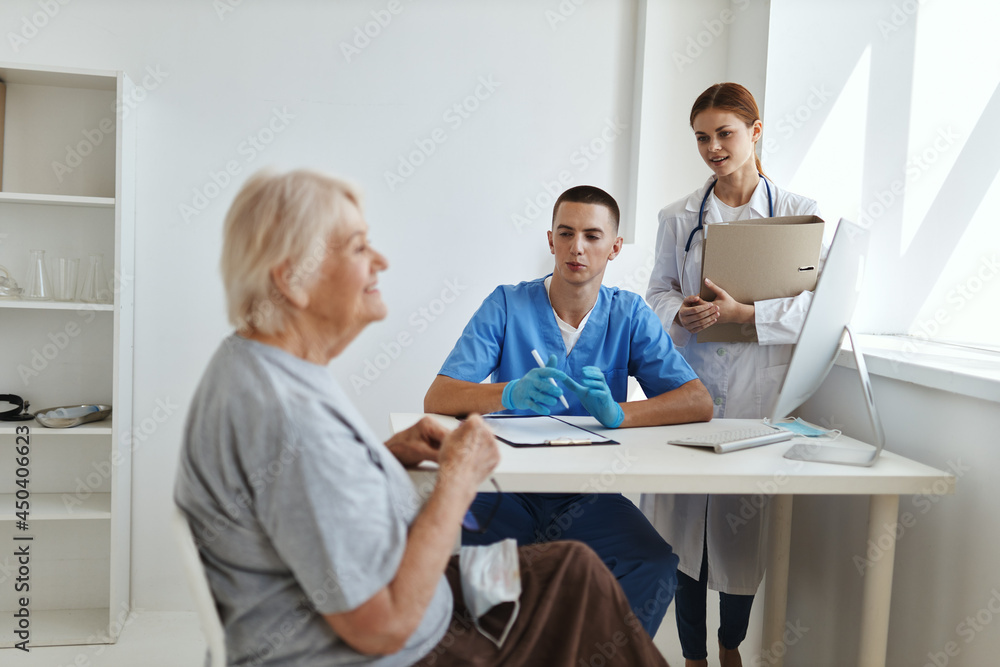 male doctor with a nurse examining an elderly woman