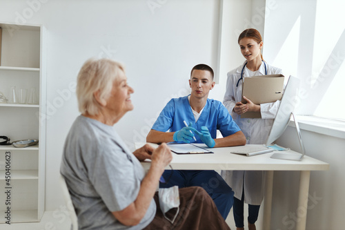 male doctor with a nurse examining an elderly woman