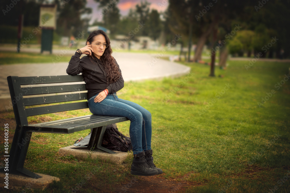 Obraz premium Young woman sitting on a park bench