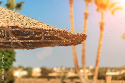 Straw umbrellas against the sky with view at palm trees