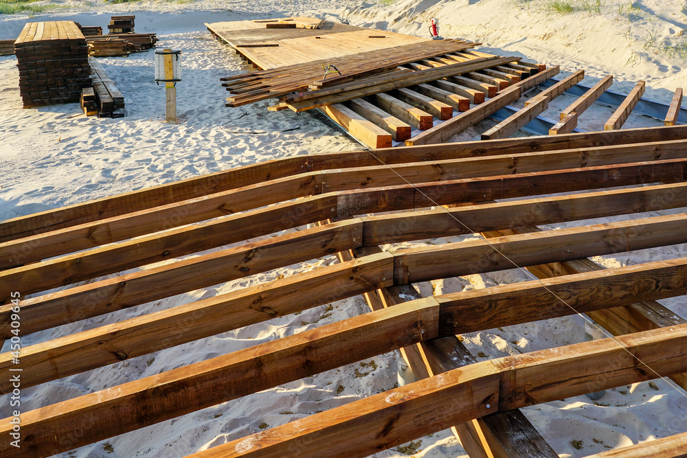 construction of a new wooden terrace floor in the sand of the beach construction of a new wooden terrace floor in the sand of the beach