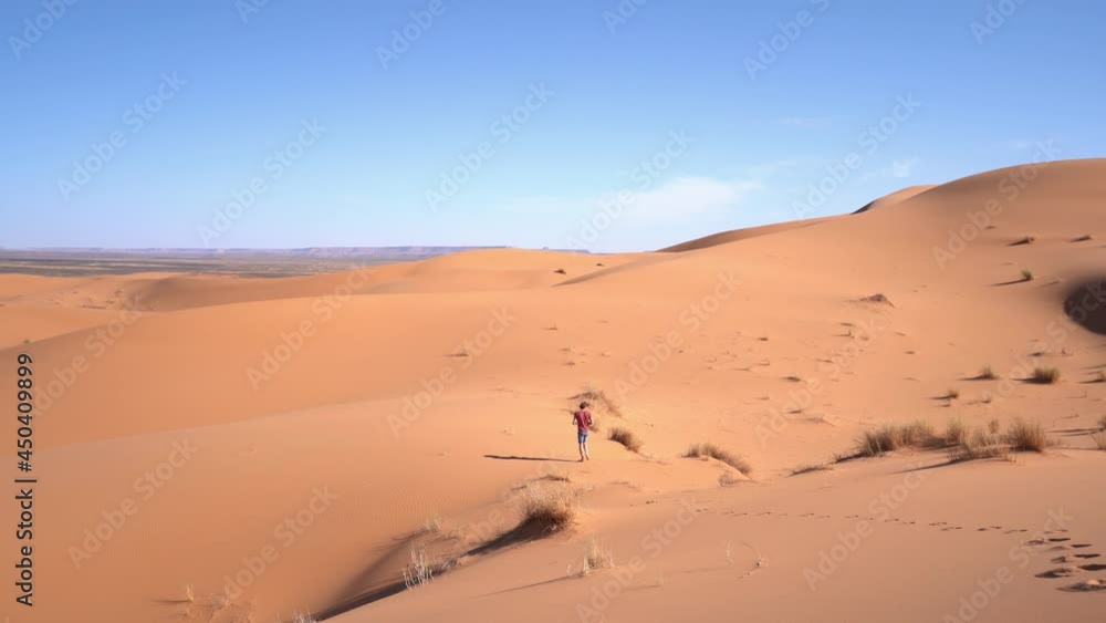 Isolated man walks by himself in the Sahara desert on a sunny day, Isolated man walks by himself in the Sahara desert on a sunny day,