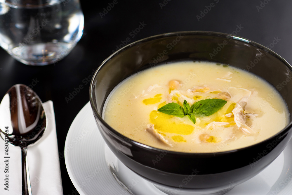 Creamy chicken soup on a black plate on a dark background. Creamy chicken soup on a black plate on a dark background.