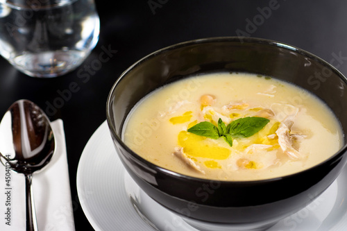 Creamy chicken soup on a black plate on a dark background.
