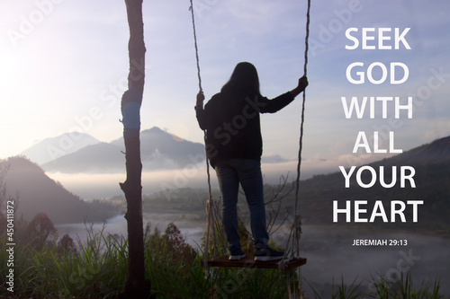 Bible verse quote - Seek God with all your heart. Jeremiah 29:13 With woman standing on natural wooden swing with misty morning view in the mountain. Christianity concept. photo