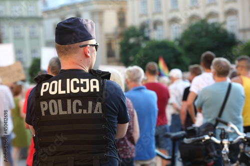 Polish policeman officer in uniform watching protesting people in the street 
