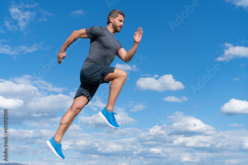 energetic man athlete with muscular body run in sportswear outdoor on sky background, motivation.