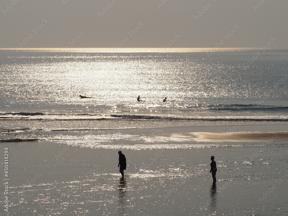 morning beachcombers and surfers in coastal Maine