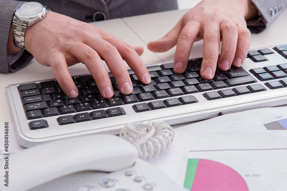Finance professional working on keyboard with reports Finance professional working on keyboard with reports