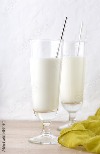 Vertical image of traditional indian milk drink in two glasses on brown wooden table with yellow cloth. Lassi made from yogurt with water, spices and ice. Ayran or kefir on white background