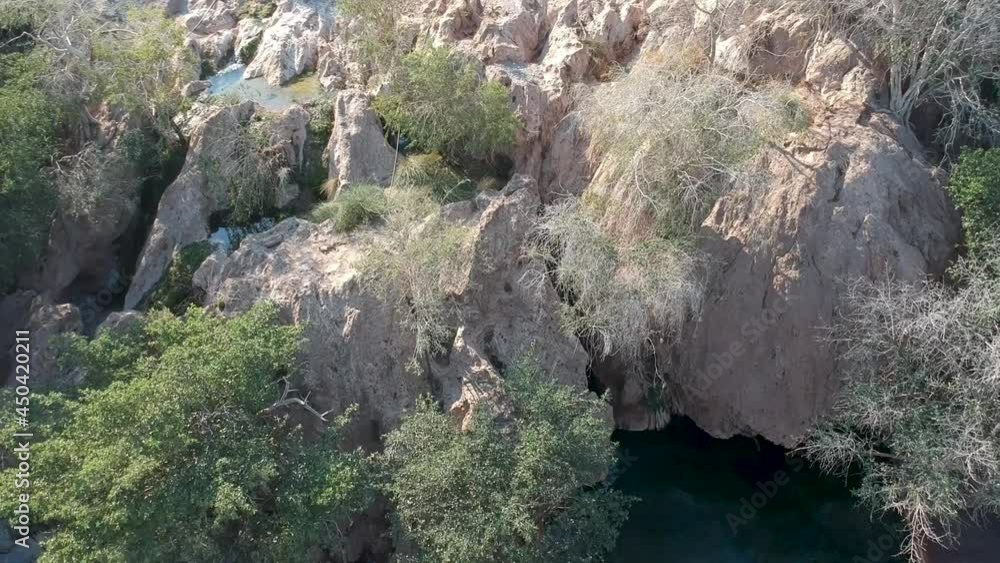 Panning down a small river running through a rocky desert landscape to a Natural pool Aerial Video Panning down a small river running through a rocky desert landscape to a Natural pool Aerial Video
