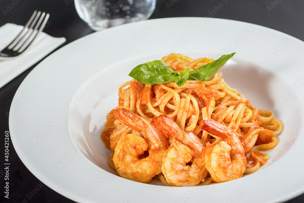 Pasta with jumbo shrimp on a white plate on a black background. Pasta with jumbo shrimp on a white plate on a black background.