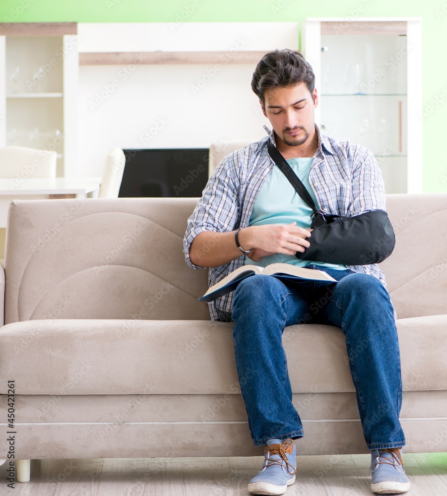 Young student man with hand injury sitting on the sofa