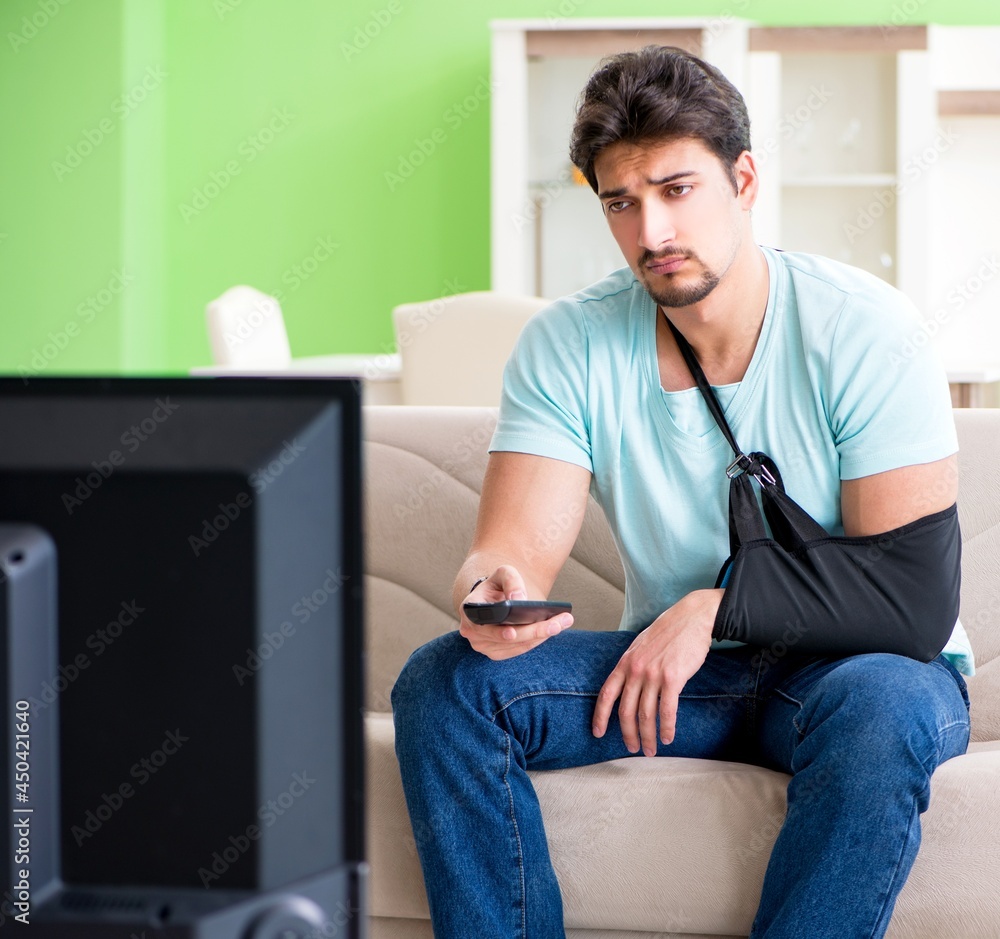 Fototapeta premium Arm injured man sitting on the sofa watching tv