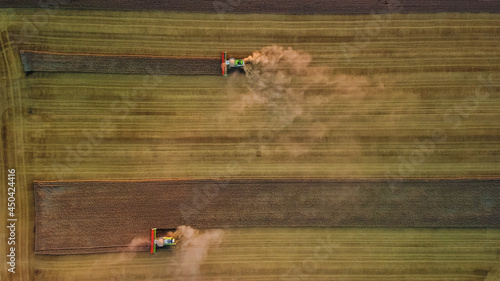 Aerial view of modern harvesters working in a field. Combines harvest wheat in the field at sunset.