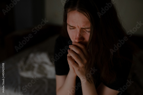Woman praying to God at night in apartment