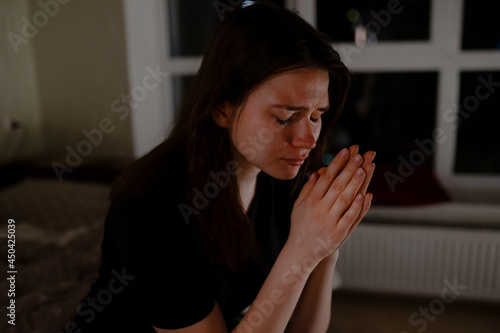 Teenager praying to God at night in apartment