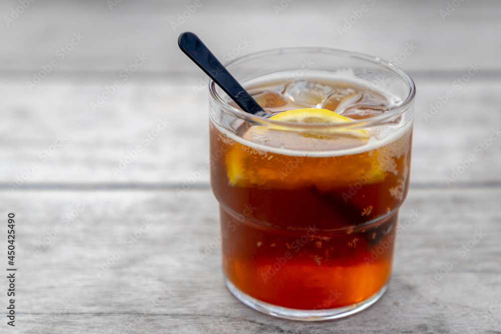 Selective focus a glass of iced tea served with sliced yellow lemon, Homemade cold drink on the wooden table, Refreshing cool drink in summer. Selective focus a glass of iced tea served with sliced yellow lemon, Homemade cold drink on the wooden table, Refreshing cool drink in summer.