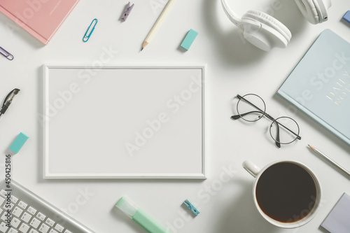 Online learning education, freelance and office work minimalistic flat lay with empty frame for text place. Stationery, headphones, notebook, pencil, glasses and coffee cup on white background.