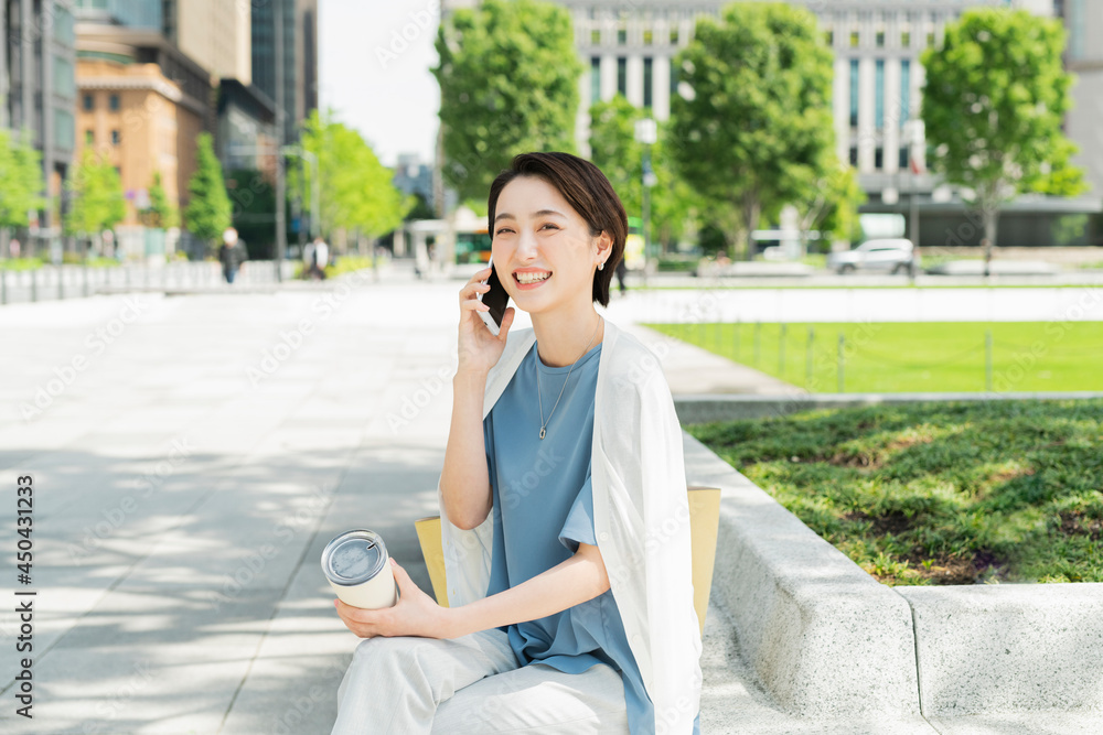 駅前で電話をする女性 駅前で電話をする女性