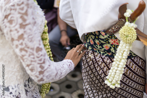 Traditional Javanese Wedding Procession, the Bride Pull Out Groom's Keris photo