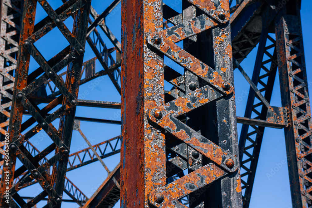 Rusty metal beams for train tracks bridge with blue sky