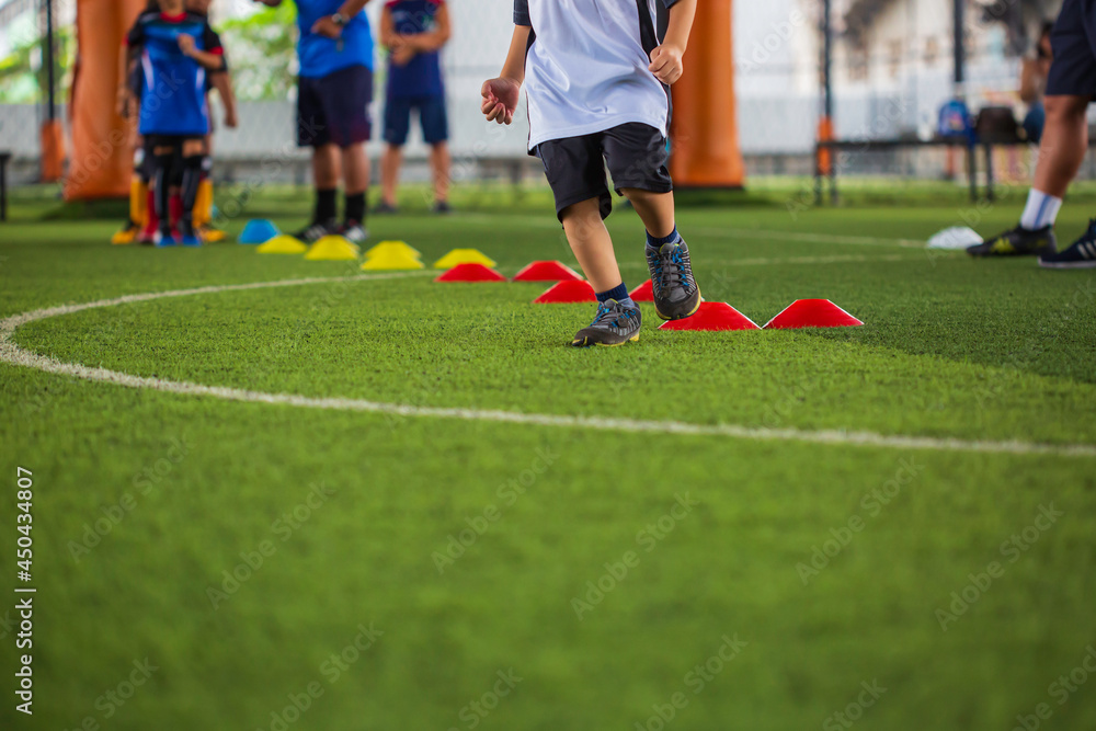 Obraz premium Soccer ball tactics on grass field with barrier for training children jump skill