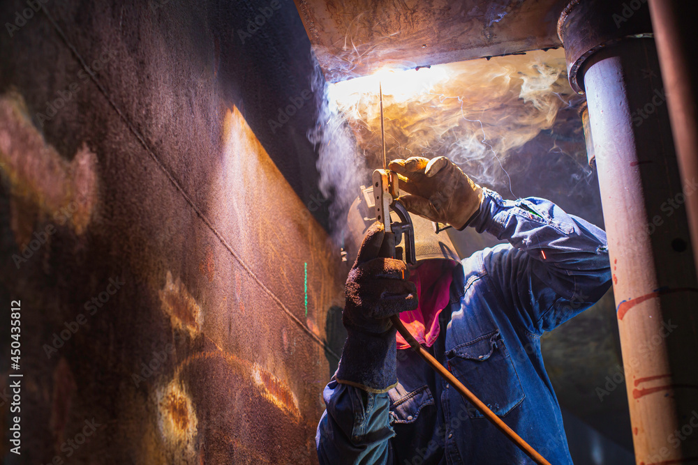Welding male worker metal arc is part in machinery tank nozzle pipeline construction tank oil inside confined spaces. Welding male worker metal arc is part in machinery tank nozzle pipeline construction tank oil inside confined spaces.