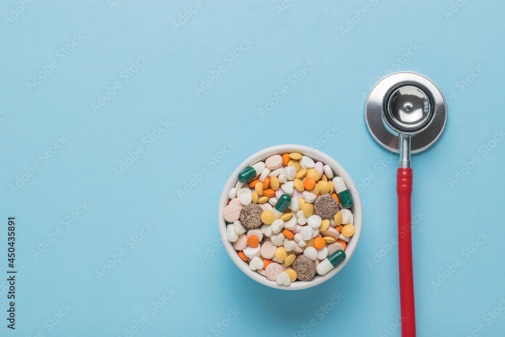A stethoscope and medical preparations for the treatment of various diseases on a blue background. Space for the text. Flat lay. A stethoscope and medical preparations for the treatment of various diseases on a blue background. Space for the text. Flat lay.