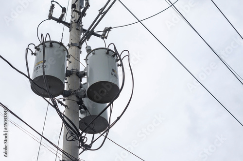 Three single-phase pole-mounted distribution transformers. During an overcast sky or before a storm. photo