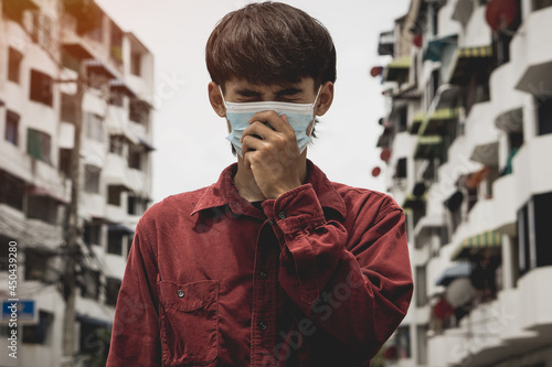 Young asia man can't breathe because wearing the respiratory protection mask against air pollution and dust particles exceed the safety limits.environmental, ecology concept.headache.
