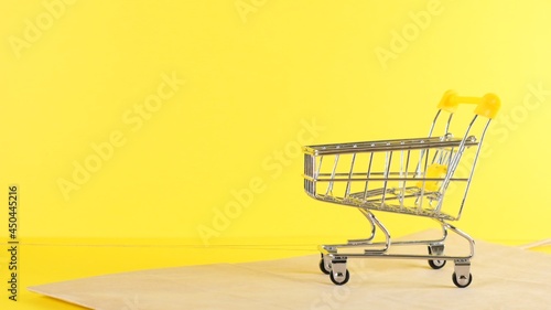 empty Shopping cart on a yellow background, closeup. Black Friday Shopping and Discount Concept