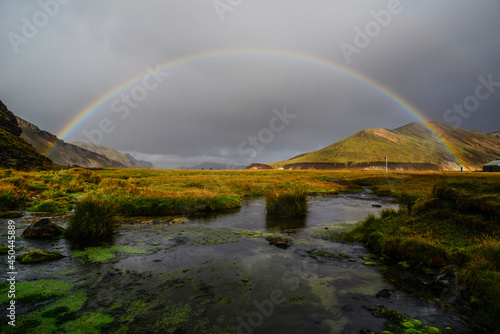 A rainbow at sunset above a pond near the Landmannalaugar hut and camping sites, Fjallabak Nature Reserve, Central Highlands, Iceland