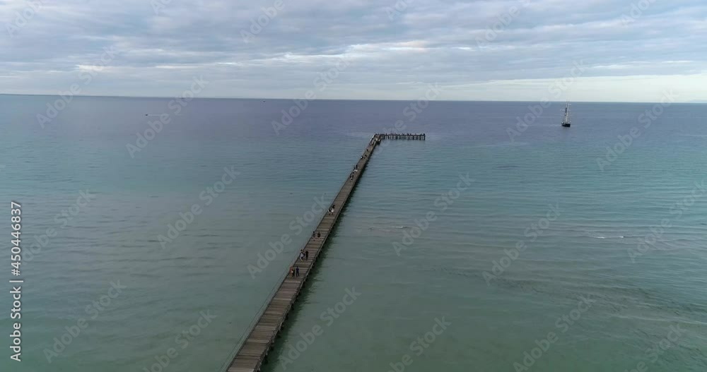 Drone Overlooking long pier and blue ocean with old sailing ship Rye Drone Overlooking long pier and blue ocean with old sailing ship Rye